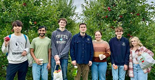 Lab members are standing in front of apple trees with apples